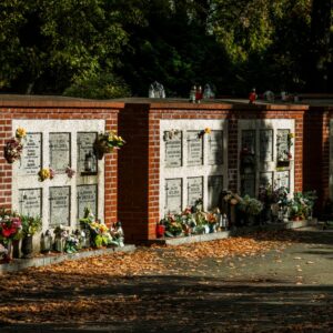 Sunlit cemetery niches adorned with flowers and candles in a tranquil outdoor setting.